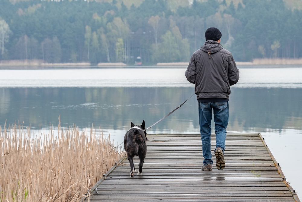 A man with his dog for a walk by the water