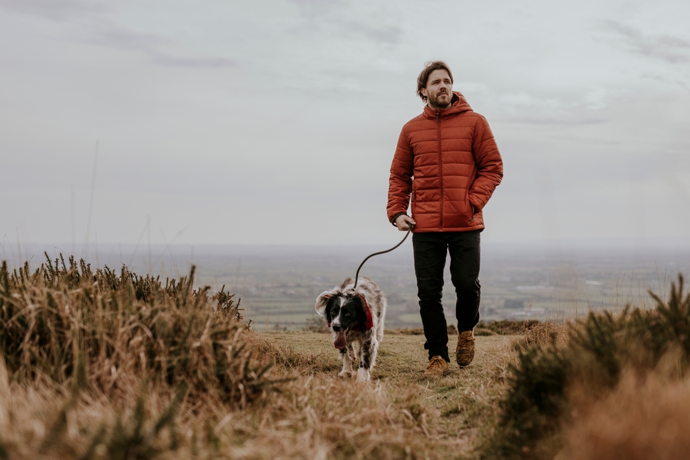 Mature white man walking dog on outdoor nature hill